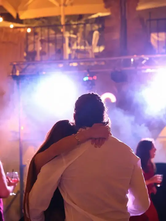 Pareja abrazada en la fiesta de una boda con luces y humo