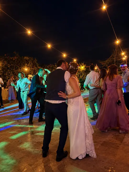 Los novios bailando abrazados en la pista en una boda de noche, con luces de colores