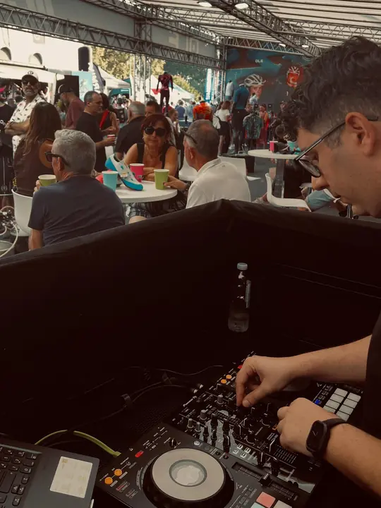 DJ pinchando en un evento corporativo bajo una carpa con mucha gente
