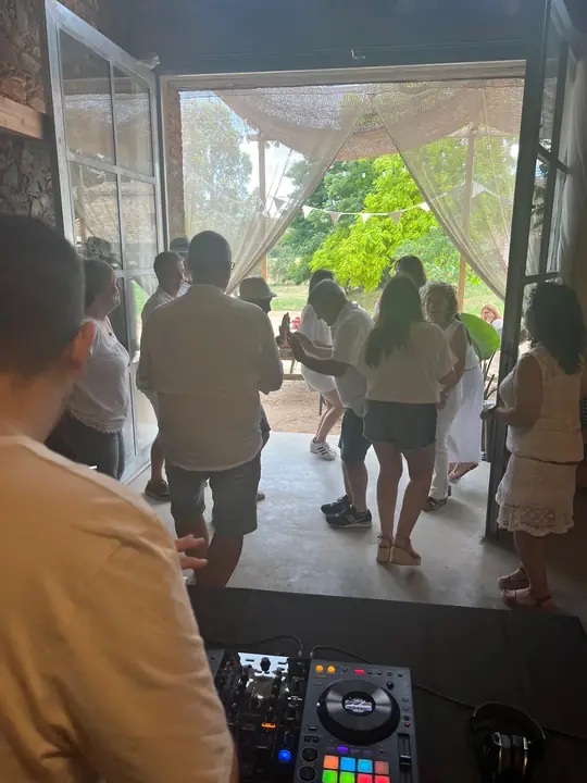 Invitados bailando en una fiesta privada al aire libre con el DJ en la mesa de mezclas