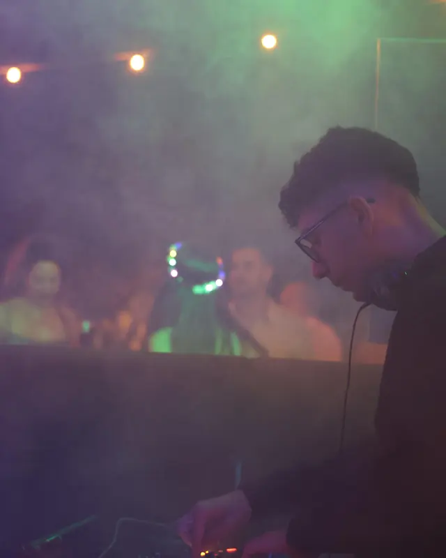 Sownder DJ pinchando en una discoteca con humo y luces