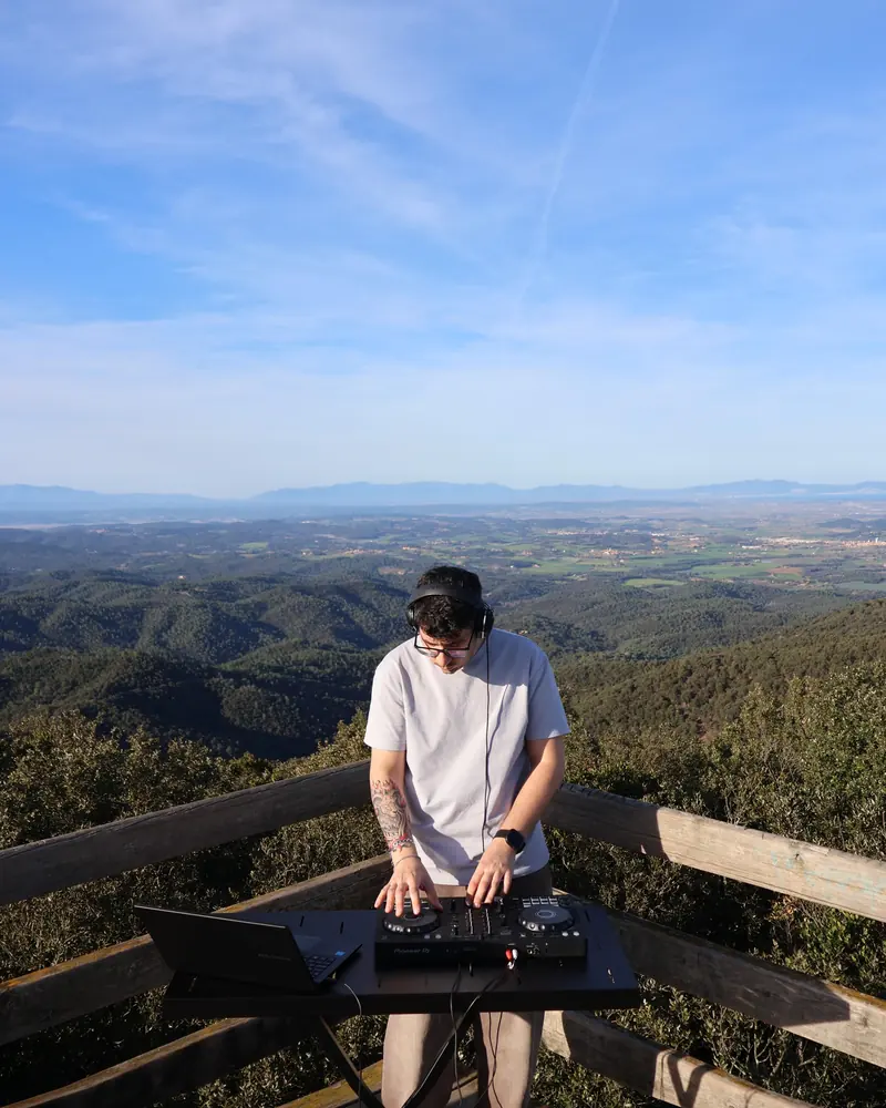 DJ pinchando en un mirador de montaña con vistas al paisaje